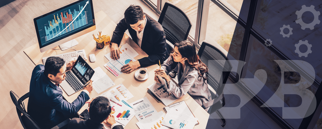 Marketers gathered together reviewing business charts on a screen